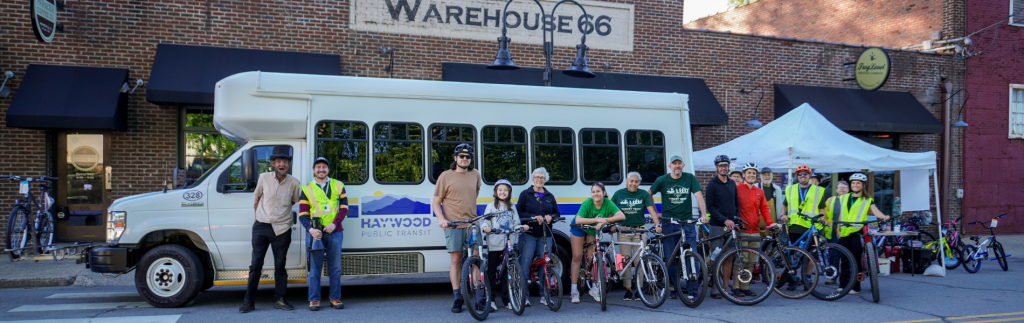 A group of cyclists gathered in front of a Haywood Public Transit bus outside of Frog Level Brewing in Waynesville during Strive Not to Drive Week, 2025.